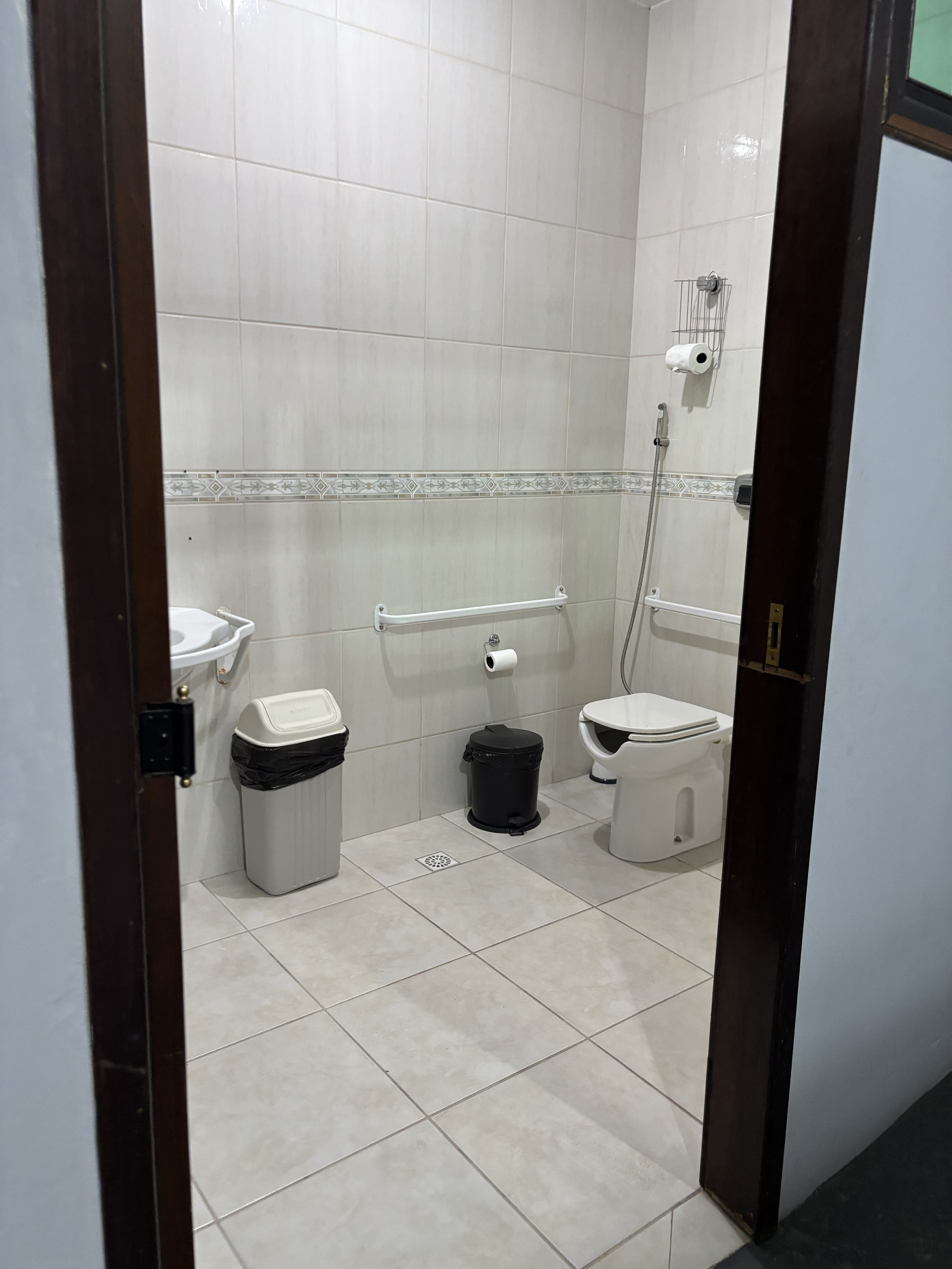 Banheiro adaptado com porta larga aberta, barras de apoio laterais e vaso sanitário suspenso