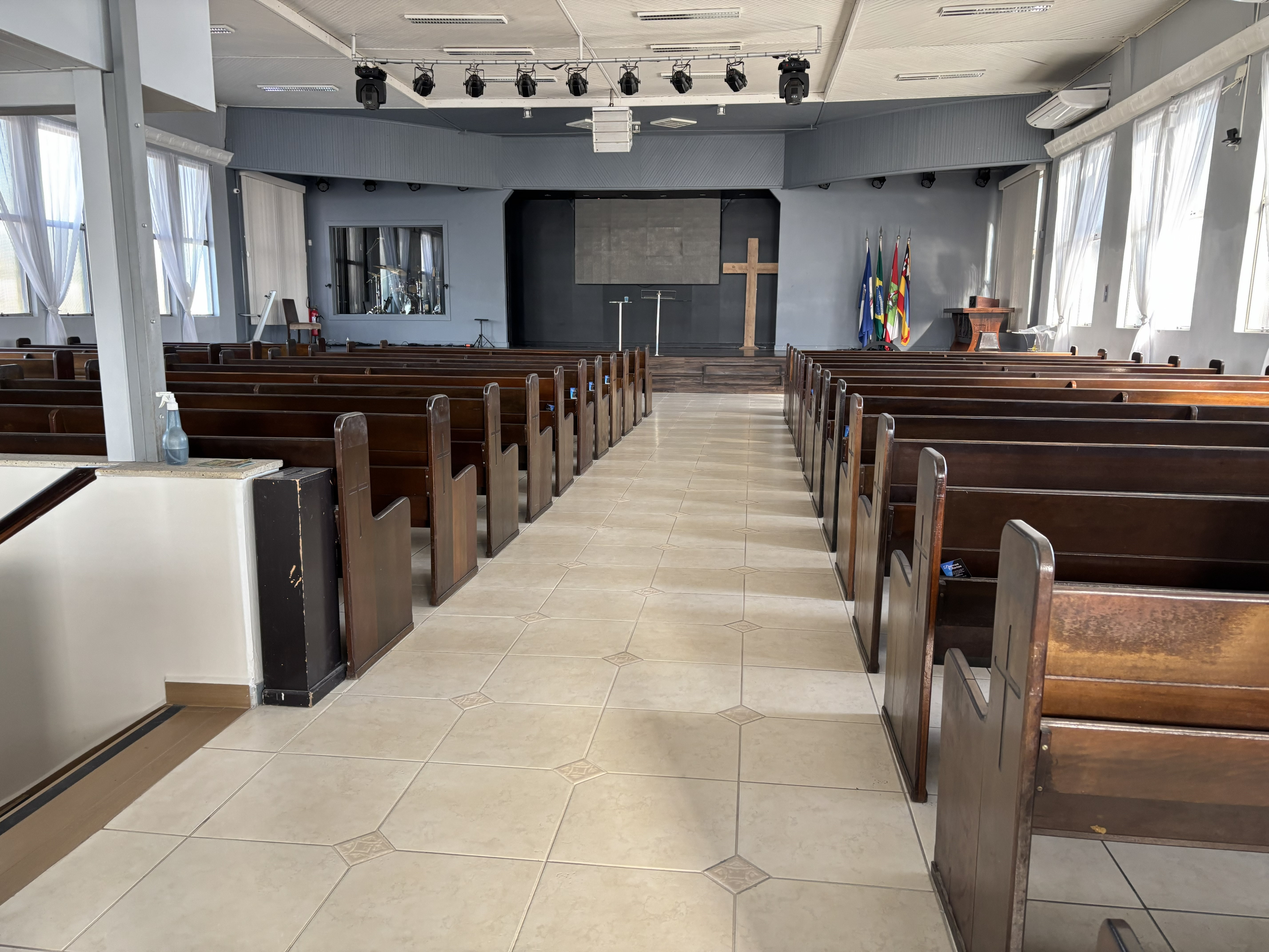 Corredor central amplo do templo com bancos de madeira nas laterais e altar ao fundo
